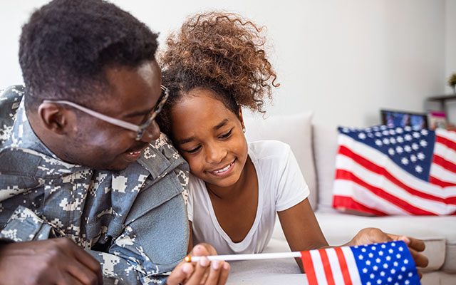 A military father and his daughter with an American flag in the background